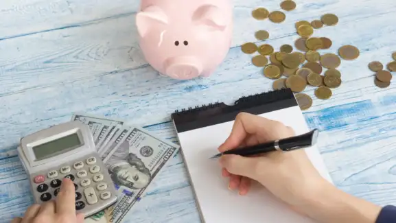a person writing on a notepad taking tips on budgeting for living expenses