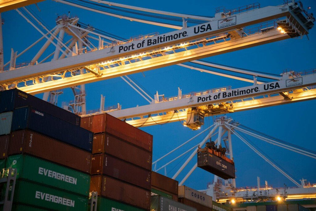 A crane hoists a container, representing the logistics of moving cargo to the USA.