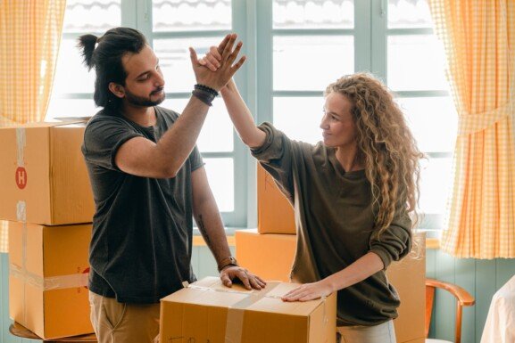 man and woman high-five as they pack and ready to move to another country
