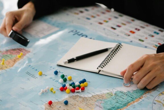 A woman's hand is placed on a map with various pins, illustrating the Best Relocation Destinations for relocation planning.