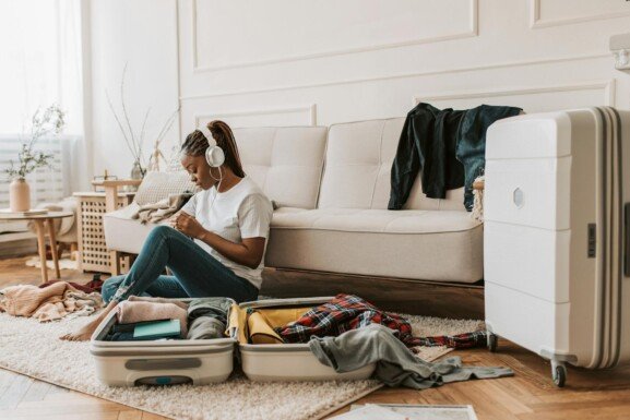 a woman sitting in her living room listening to music while packing for an international move
